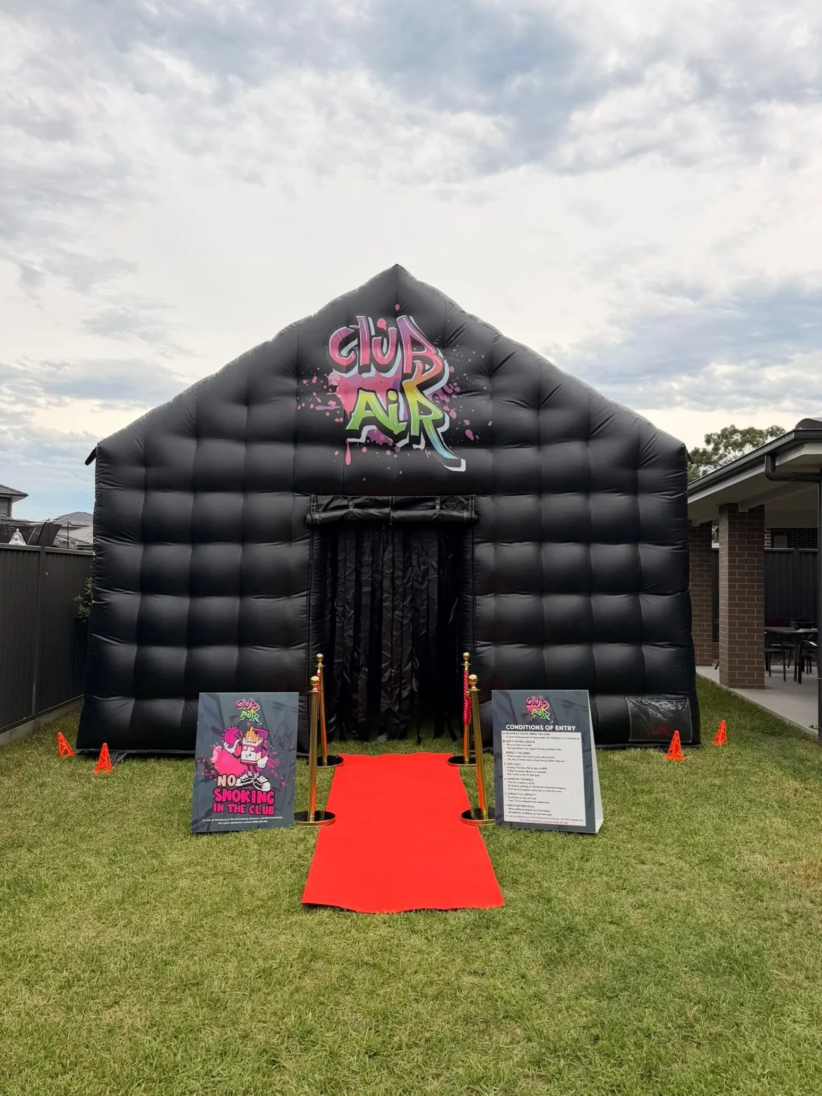 Club Air inflatable nightclub front view with graffiti logo, gold bollards and red carpet rolled out on grass in western Sydney