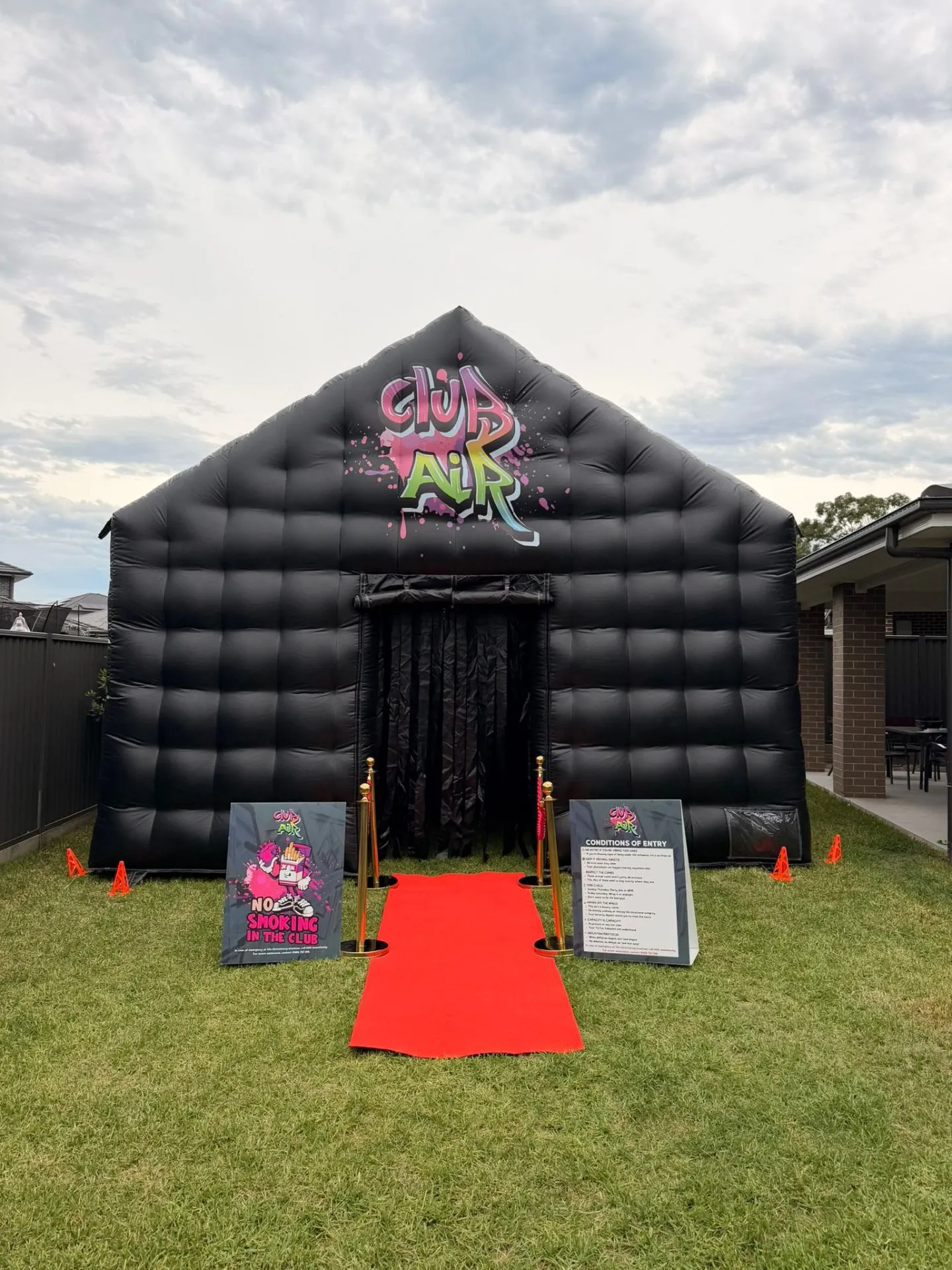 Club Air inflatable nightclub front view with graffiti logo, gold bollards and red carpet rolled out on grass in western Sydney